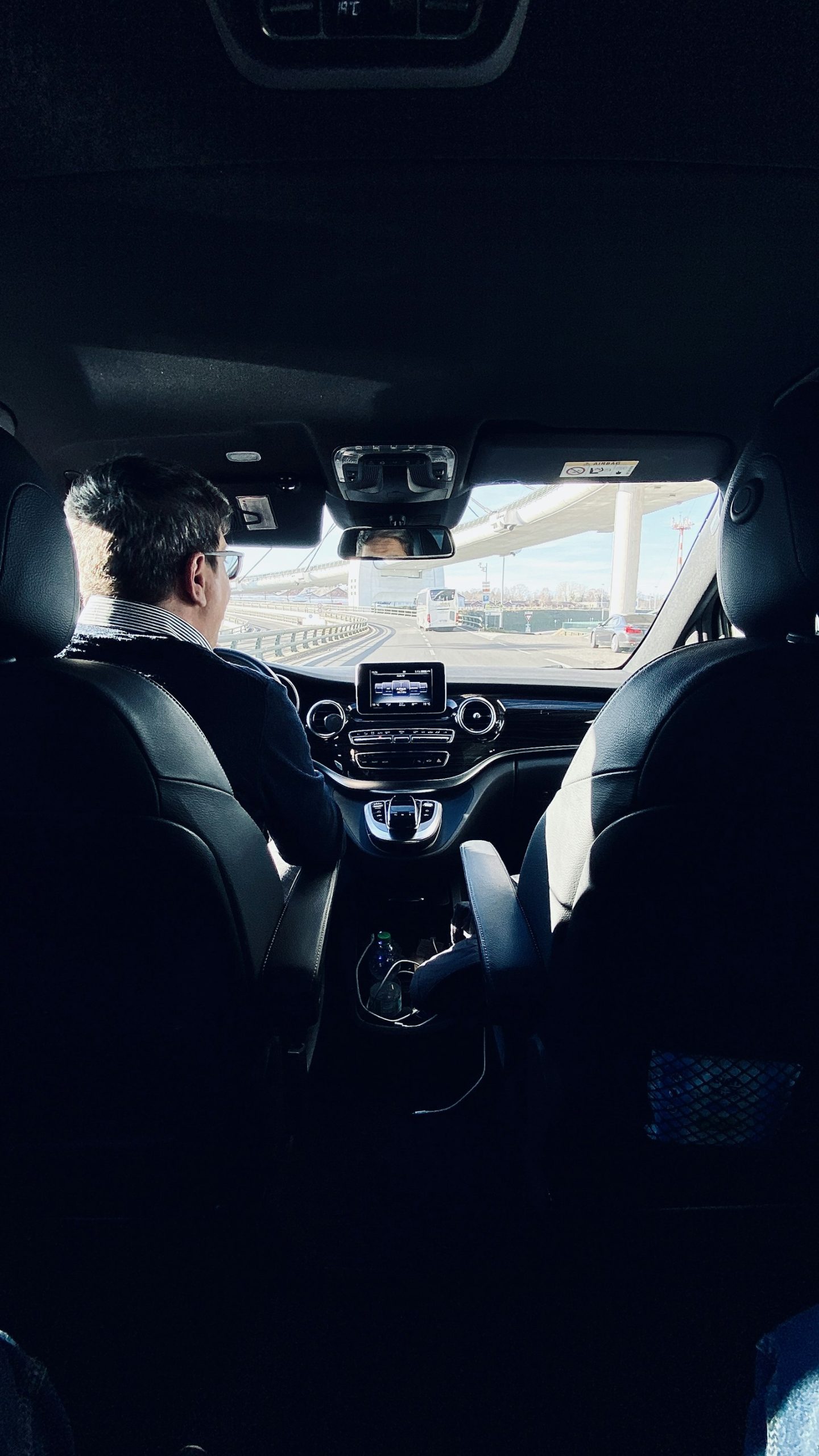 Professional chauffeur in a suit driving a luxury car