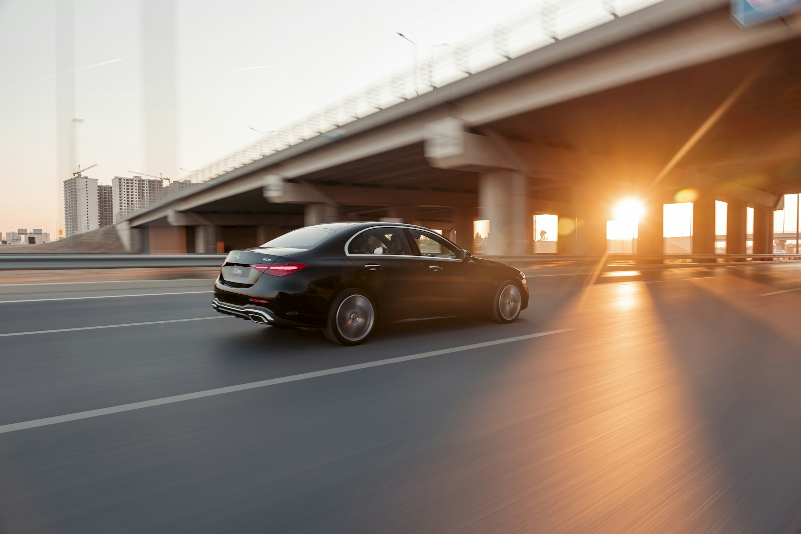 Black luxury car driving through the city at sunset